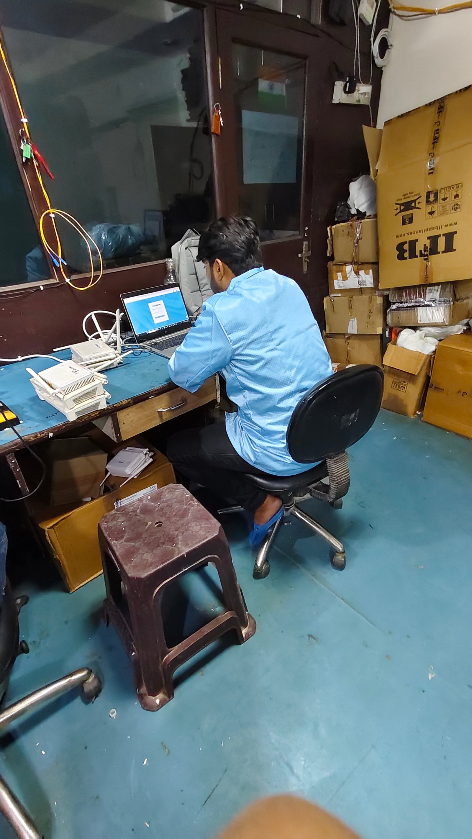 Technician configuring repaired networking devices with a laptop
