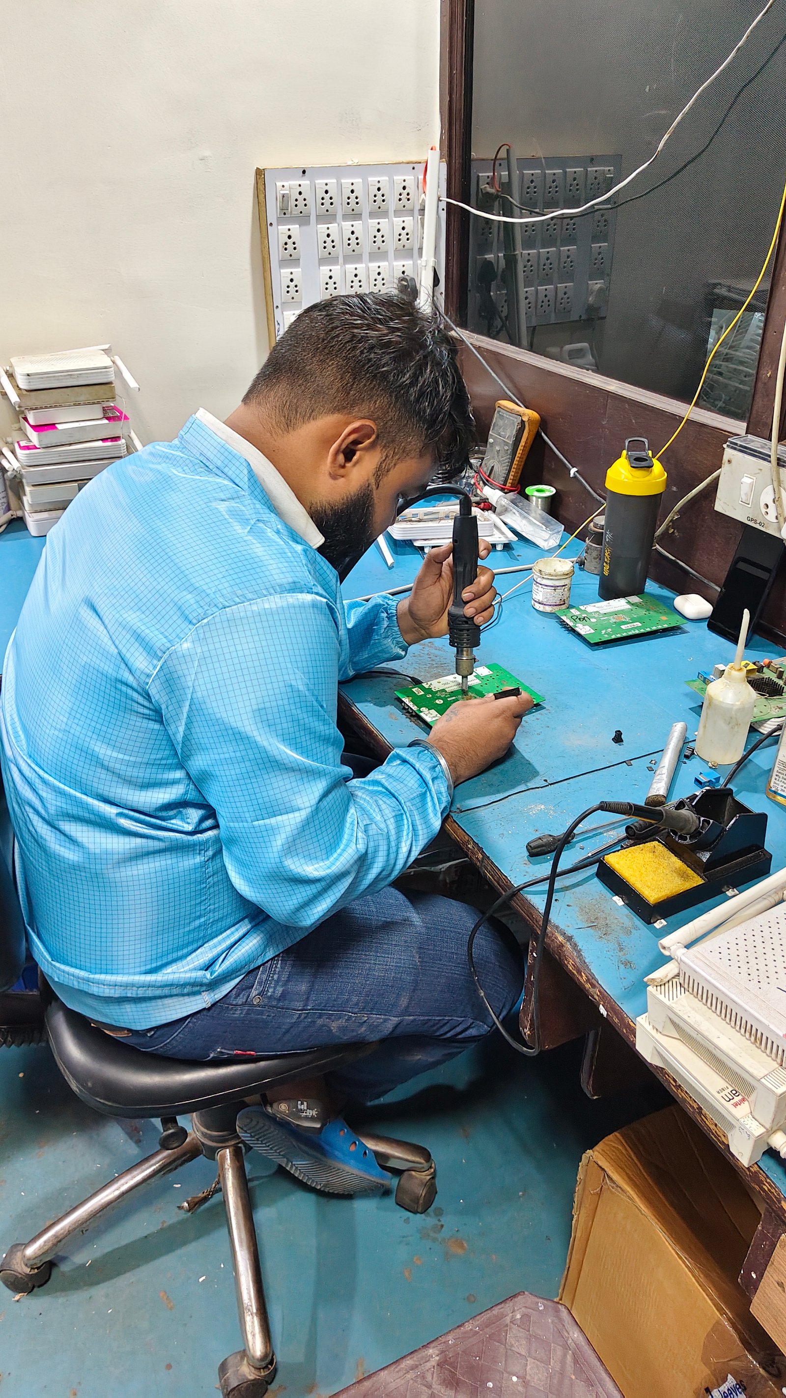 Technician using a hot-air rework tool on a circuit board